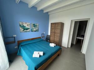 um quarto azul com uma cama com duas toalhas em Villa NATURE ZAGARA SCOPELLO ZINGARO em Castellammare del Golfo