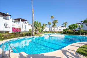 basen z błękitną wodą i palmami w obiekcie Genteel Home Guadalvillas w Marbelli