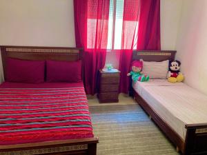 Appartement beau et familial connecté في طنجة: سريرين في غرفة نوم مع ستائر حمراء