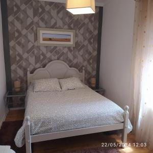 een slaapkamer met een wit bed en een muur bij Oeste Casa in Vale Covo