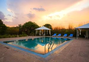 a swimming pool with chairs and a gazebo at Moustache Ranthambore Luxuria in Sawāi Mādhopur