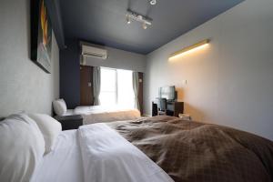 um quarto de hotel com duas camas e uma janela em Residence Hotel Naha West em Naha