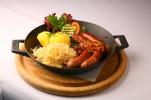a pan filled with food on a wooden plate at Der Teichhof in Grandenborn