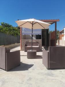 un patio con sombrilla, sillas y mesa en Villa Elvira, en Vieste