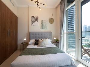 um quarto com uma cama grande e uma janela grande em Luxe Apartments near Dubai Mall Burj Khalifa Pool Gym Parking em Dubai