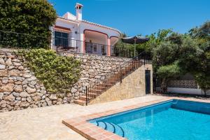 een huis met een zwembad naast een stenen muur bij Villa Mimosa in Cómpeta