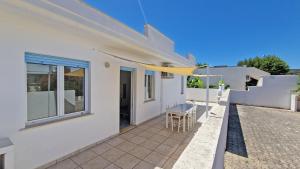 a white house with a balcony with a table and chairs at Residence La Corte by Salento Affitti in Marina di Mancaversa