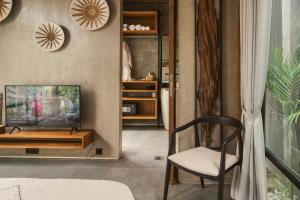 a living room with a tv and a chair at Danu Villas Bali in Kerobokan