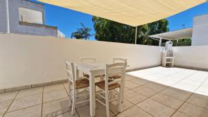 a white table and chairs on a patio at Residence La Corte by Salento Affitti in Marina di Mancaversa