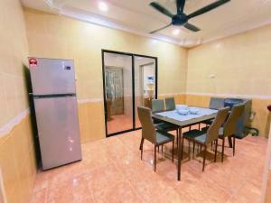 ein Esszimmer mit einem Tisch und Stühlen sowie einem Kühlschrank in der Unterkunft Area Indahpura or Taman Bersatu Kulai 3-4BR near AEON Airport JPO in Kulai