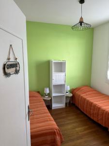 a bedroom with two beds and green walls at Maison de ville plein centre, 3 étoiles, à 200m de la plage, parking privé, WIFI in Royan