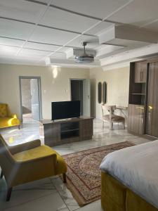 a bedroom with a bed and a tv and a living room at Polokwane Estate Lodge & Spa in Polokwane
