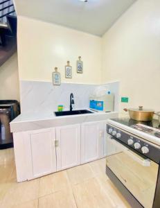 eine weiße Küche mit Spüle und Herd in der Unterkunft 3 Bedroom House near Davao Airport in Davao City + 8 Fotos