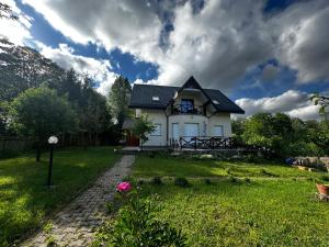 Biały dom z czarnym dachem na zielonym dziedzińcu w obiekcie Leśny Zdrój w Polanicy Zdroju