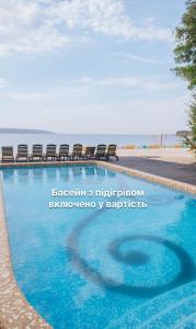 a swimming pool with chairs and the ocean in the background at Secret Resort Club in Pereiaslav-Khmelnytskyi