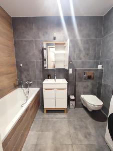 uma casa de banho com uma banheira, um lavatório e um WC. em Apartament Warneńczyka Mielec em Mielec