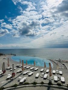 - une piscine avec des chaises et des parasols à côté de l'océan dans l'établissement Optima Collection Miramar Chornomorsk, à Tchornomorsk