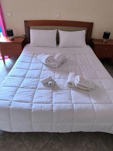 a white bed with two folded towels on it at Robert House in Samos