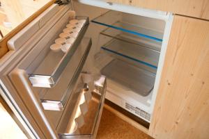 an empty refrigerator with its door open in a kitchen at Tiny House Pioneer 2 - Salemer See in Salem +17 photos