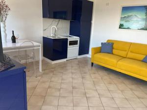 a living room with a yellow couch and a kitchen at Overlooking Lago Maggiore in Verbania +9 photos