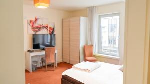 a bedroom with a bed and a desk with a television at Hotel Kleiner Markt in Saarlouis