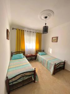 een slaapkamer met twee bedden en een raam bij Appartement près de la plage in Martil