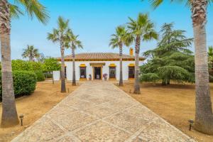 ein Weg, der zu einem weißen Haus mit Palmen führt in der Unterkunft Casa Rural Azahares de Marchena in Marchena