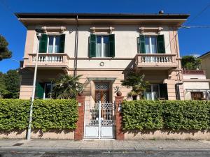 uma casa grande com um portão e arbustos em Pura vida em Viareggio