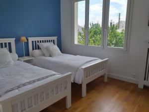 two beds in a room with two windows at Le Plongeoir in Donville-les-Bains