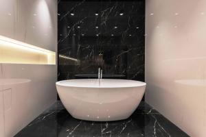 een badkamer met een groot wit bad op een zwarte marmeren vloer bij GRAND HOMESTAY in New Delhi