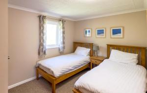two twin beds in a room with a window at Gwithian Holidays in Hayle
