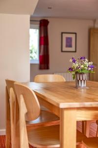 a dining room table with a vase of flowers on it at Gwithian Holidays in Hayle