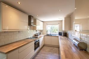 a large kitchen with white cabinets and wooden floors at Gwithian Holidays in Hayle