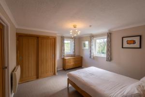 a bedroom with a bed and a dresser and two windows at Gwithian Holidays in Hayle