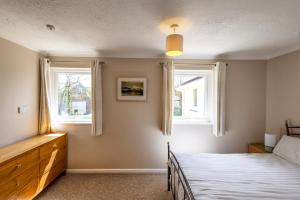 a bedroom with a bed and two windows at Gwithian Holidays in Hayle