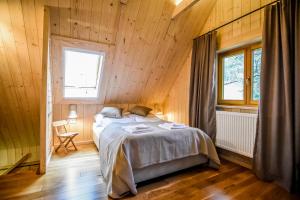 a bedroom with a bed in a wooden cabin at Sowie Domki - Domek Nad Potokiem in Kacwin