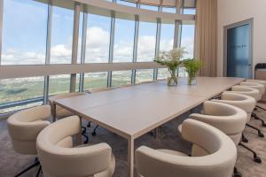 Vilnius TV Tower Apartments DEBESYS في فيلنيوس: قاعة اجتماعات مع طاولة وكراسي بيضاء