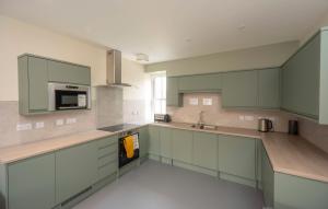 a large kitchen with green cabinets and a sink at Newcastleton Bunkhouse in Newcastleton