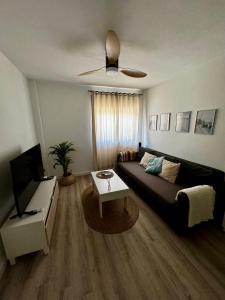 een woonkamer met een zwarte bank en een tv bij Apartamento con parking en Pedregalejo in Málaga