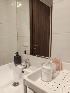 Fancy home Budapest في بودابست: حمام أبيض مع حوض ومرآة