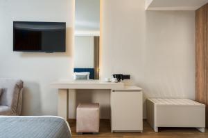 Habitación con cama, escritorio y TV. en Palatino Hotel en Zakynthos