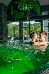 un hombre y una mujer en una piscina con agua verde en Rest&Ski Spa Resort, en Bukovel