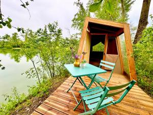 une table et des chaises sur une terrasse en bois à côté d'un lac dans l'établissement Les Etangs de la Bassée, à Gravon