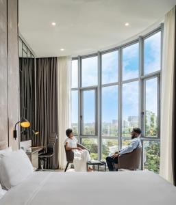 Dos personas sentadas en sillas en una habitación de hotel con ventanas en Dusit Princess Hotel Residences Nairobi, en Nairobi