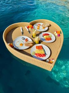 a table with breakfast food on top of the water at Makawi Tuwa Cliff - Luxury Cliff Stay with Private Beach, Infinity Pools and Ocean View in Seraya
