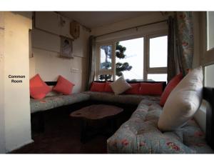 ein Wohnzimmer mit einem Sofa und einem Fenster in der Unterkunft Dom's at Mall Road, Mussoorie in Masuri
