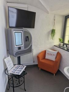 a living room with a tv and an orange chair at Velden24 - create your own stay in Velden am Wörthersee
