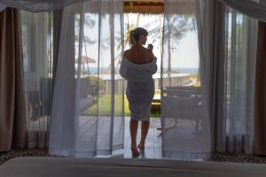 a pregnant woman in a white dress looking out of a window at GRAND OCEAN BAY RESORT PHU QUOC in Phu Quoc