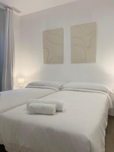塔拉戈纳Vigablanca Apartments的一间白色卧室,床上配有2条白色毛巾