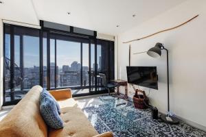 Skyline Allure - Urban Wellness meets City Living في ملبورن: غرفة معيشة مع أريكة وتلفزيون بشاشة مسطحة